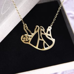 Goldene Origami Faultier Kette aus Edelstahl von Cherami auf schwarzem Schmuckhintergrund